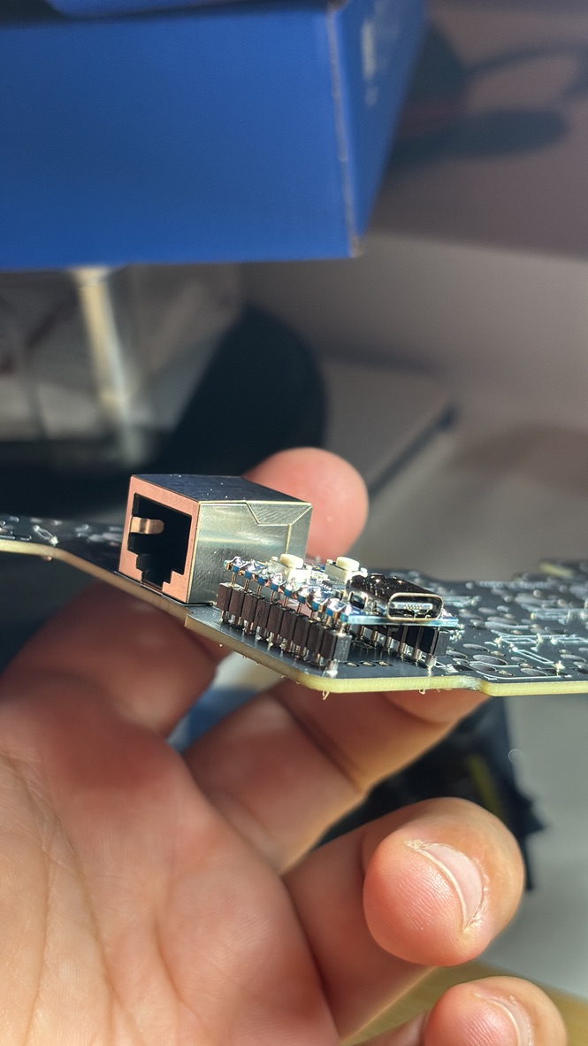 A hand holding a PCB with a chip connected into it