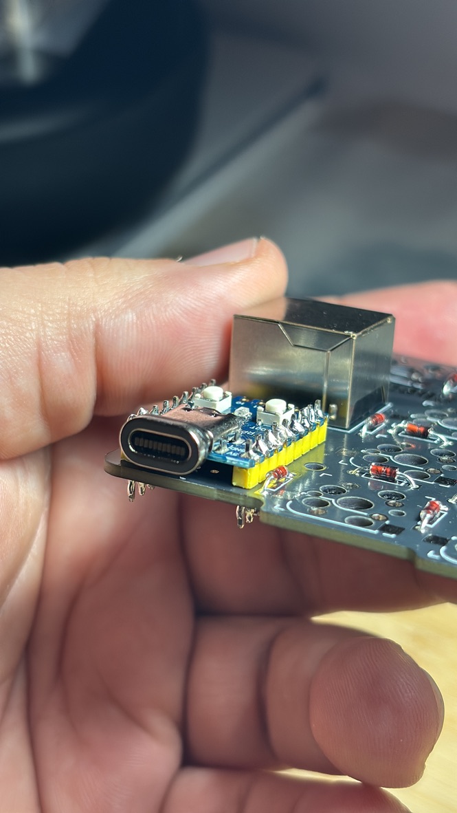 A hand holding a PCB with a chip soldered into it
